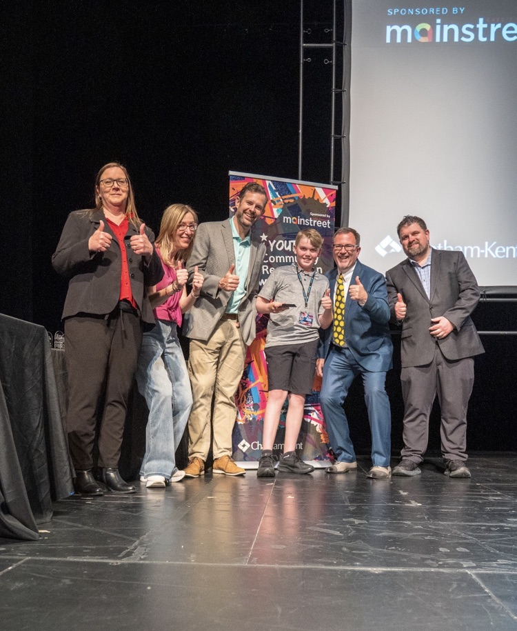 student posing with adults for award