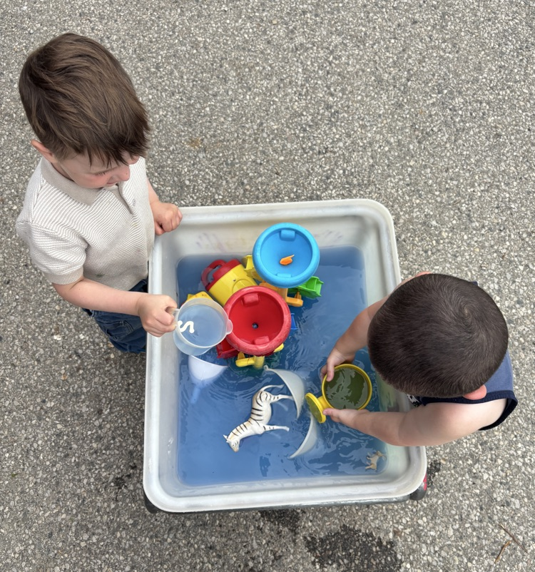 two children playing with toys in a water table