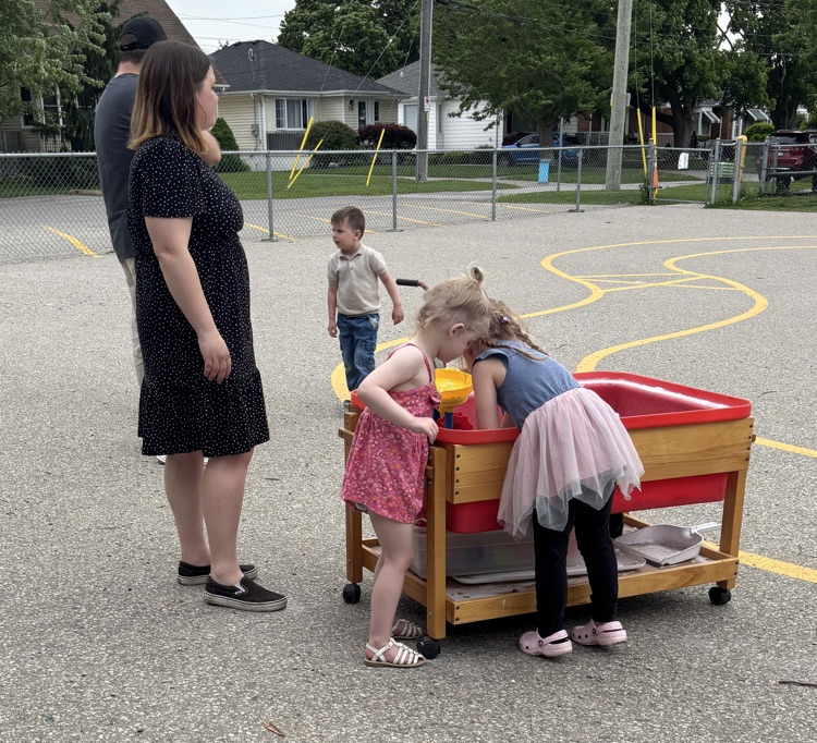 A family playing at the sand table in kindergarten