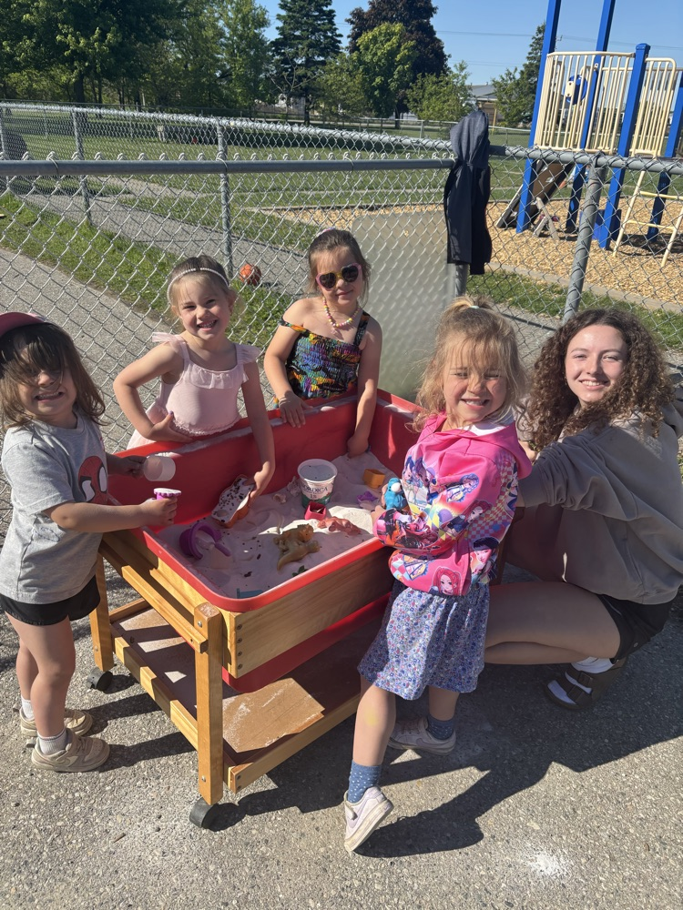 5 students playing at the sand table with their high school coop student 