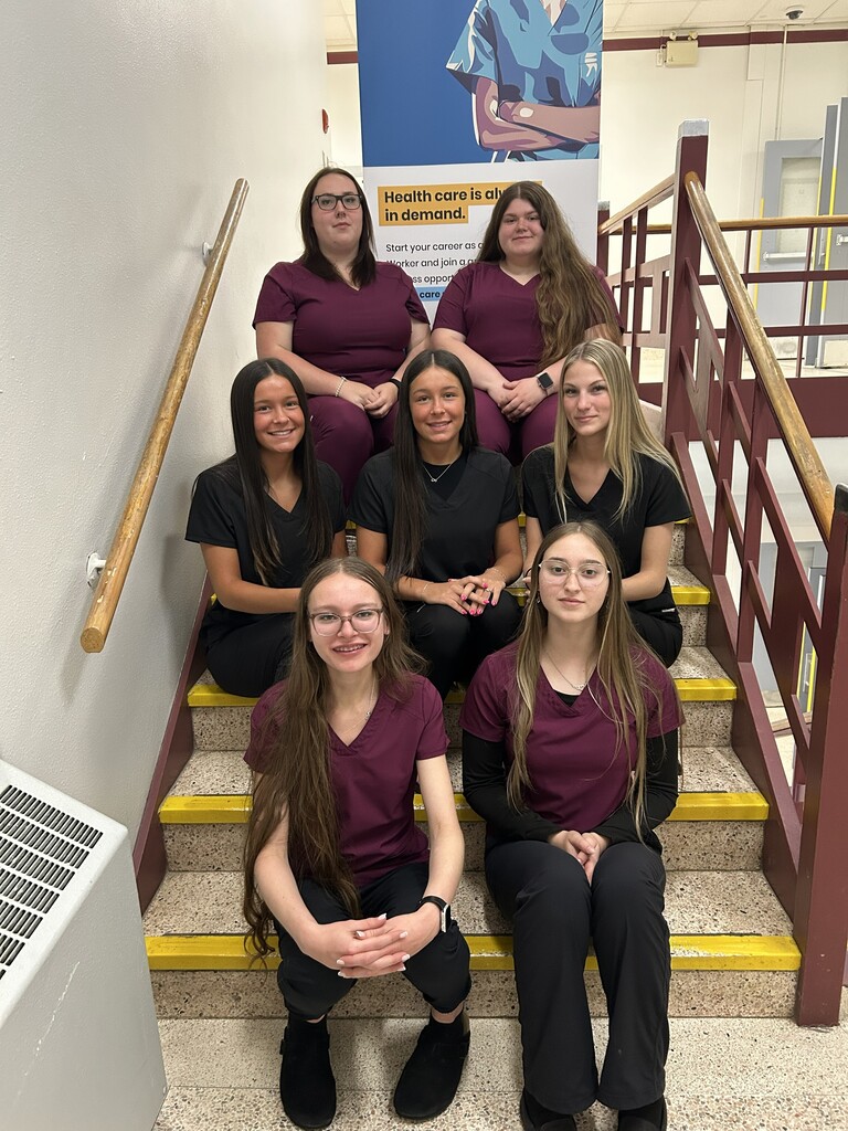 seven students sitting on the stairs, smiling