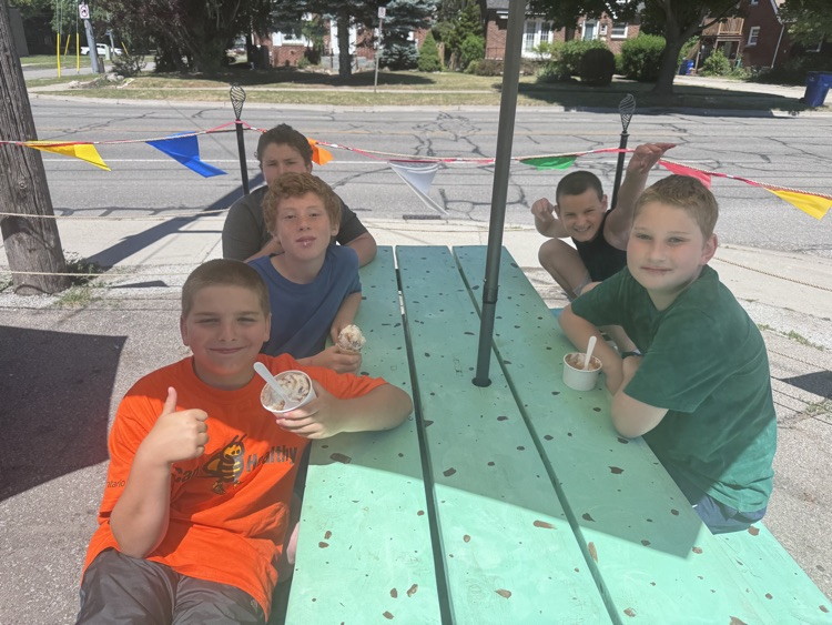 children sitting on a picnic table, eating ice