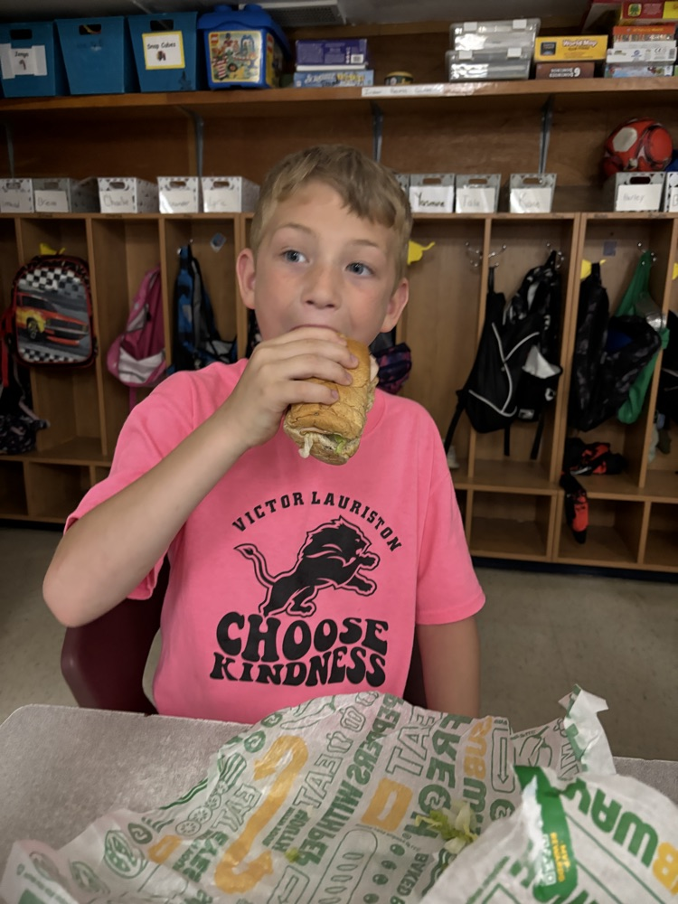 Student eating a sub wearing a pink shirt
