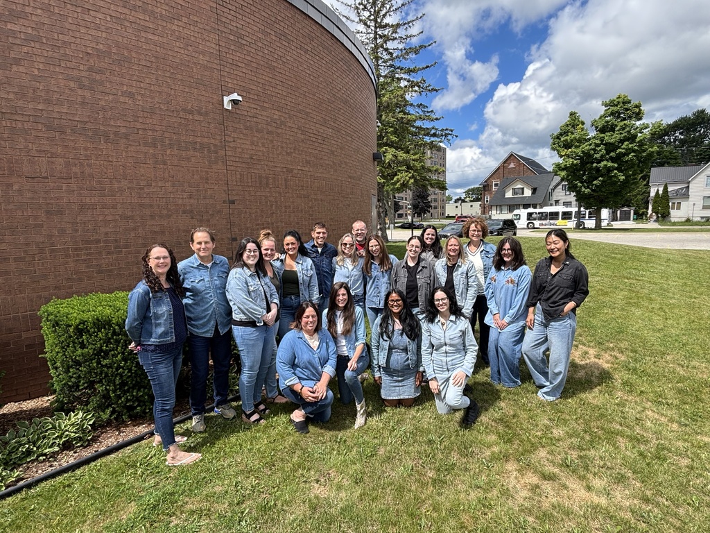 Staff at the Sarnia Education Centre wearing all denim for their spirit day titled "Canadian Tuxedo Day". They are standing outside of the building on the grass.