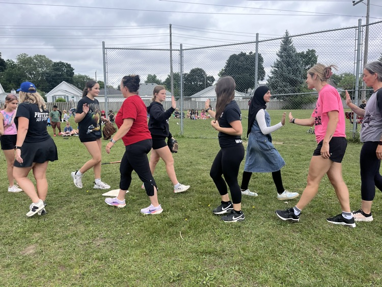 Staff and student students high-fiving each other in the middle of a baseball field