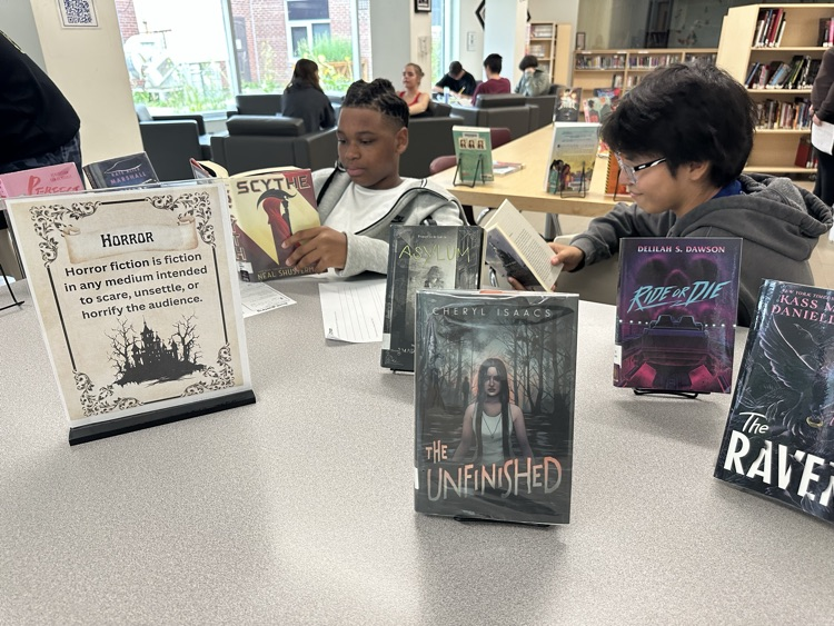 Grade 9 English students exploring books at different genre stations during a Book Tasting activity in the school library.
