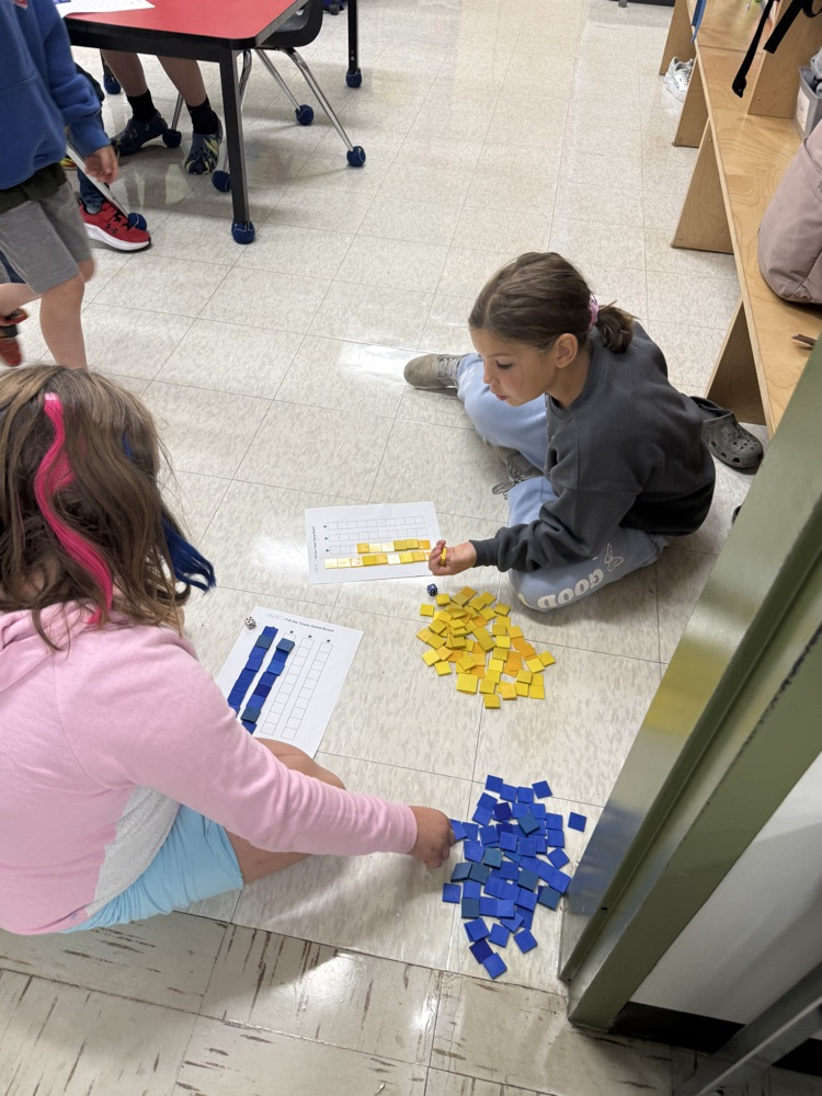 Grade 2/3 girls playing a math game on the floor of their classroom