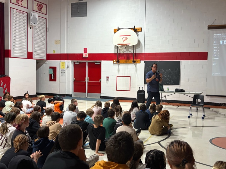 Jason Simon speaking to a gym full of students