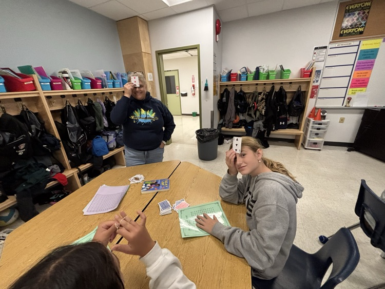 teacher and student playing a math card game with a card facing out against their foreheads