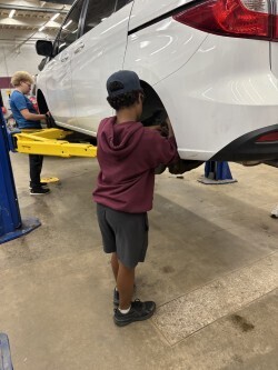 two students working on white car