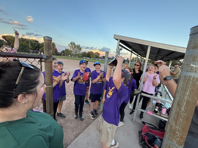 two pitch player raising the trophy with players around cheering