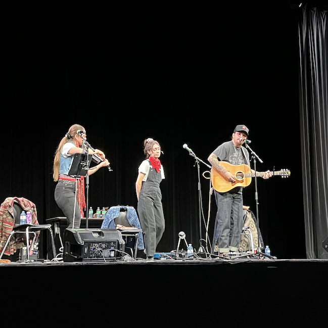 Three musicians appear on stage