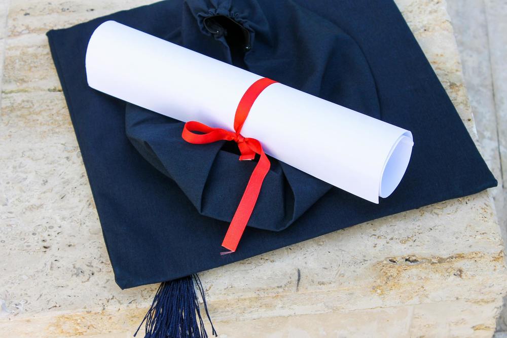A stock image of a diploma on a graduation cap