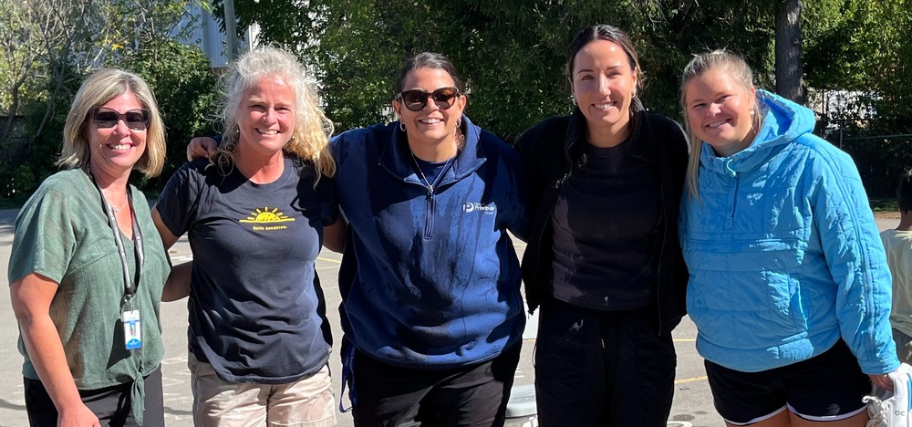 5 women who are wet but smiling after having ice cold water dropped on them.