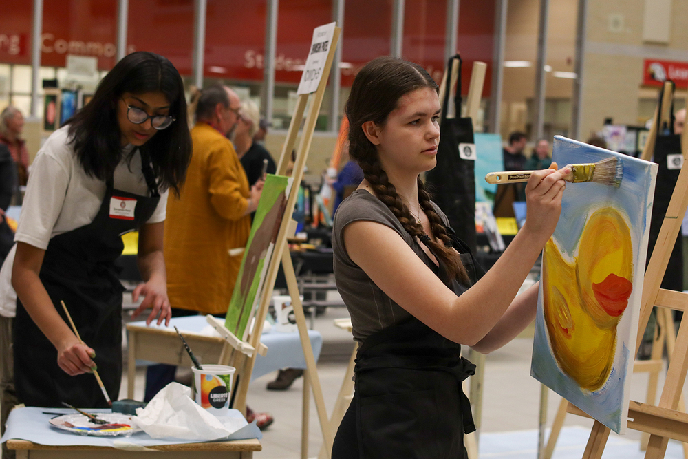 Students paint on aisles in a school gym.