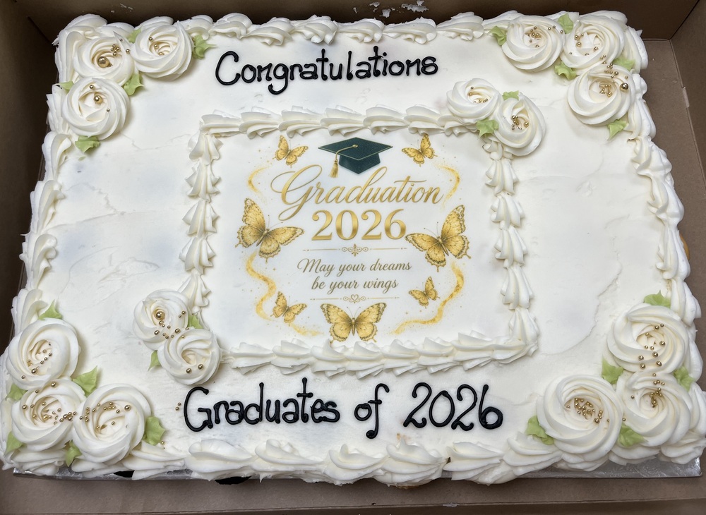 A large white graduation cake with gold decorations and golden butterflies congratulating our 2026 grads.