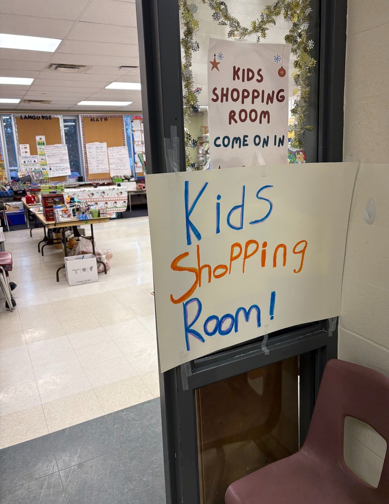 Classroom with the sign: Kids shopping room on what paper with gold garland in window.