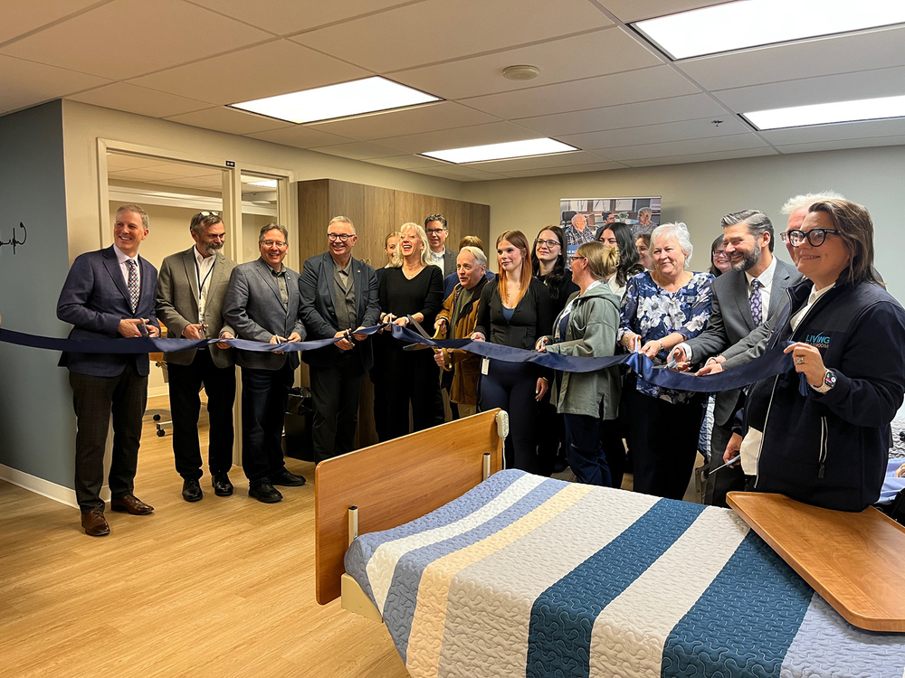 A group of people standing in a healthcare facility holding a large ribbon.