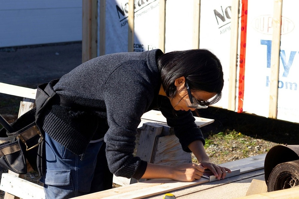 A woman with safety glasses on works on a construction project.