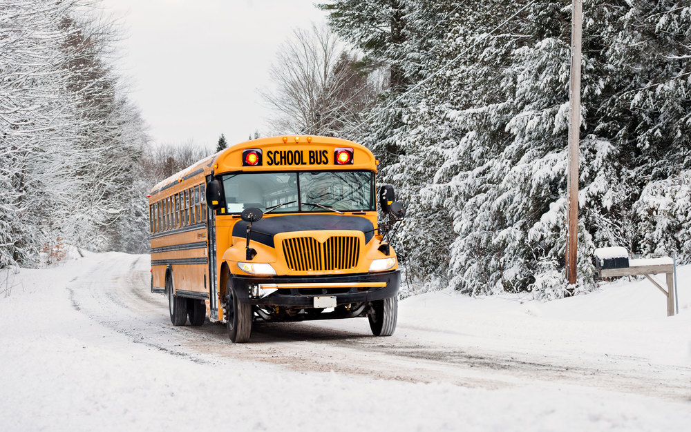 A yellow school bus driving on a snowy road