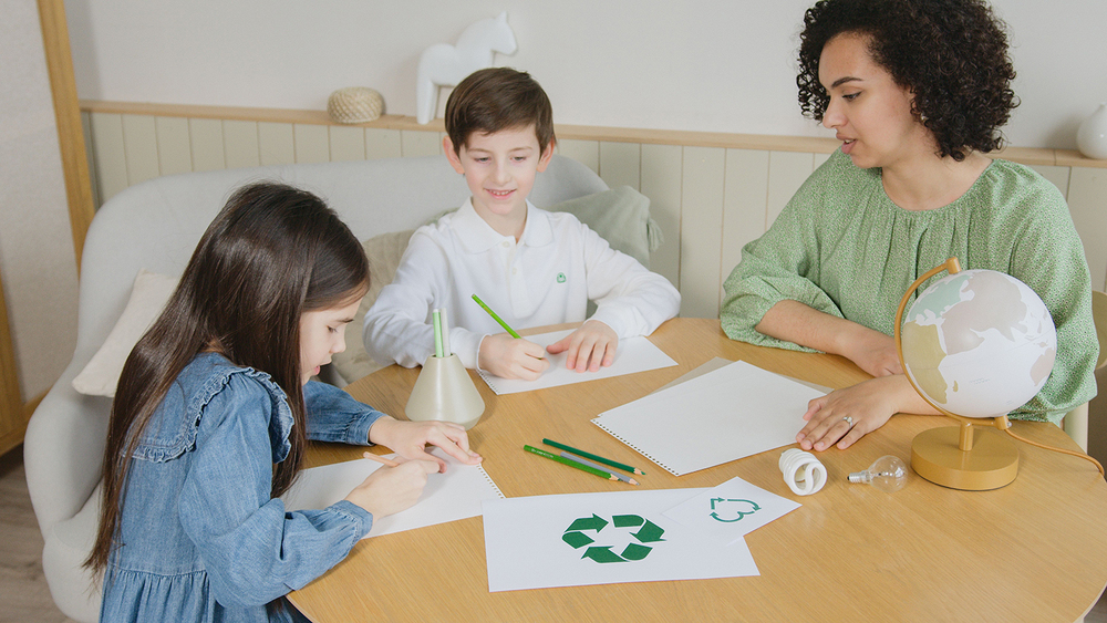 two children and one adult sit at a table drawing