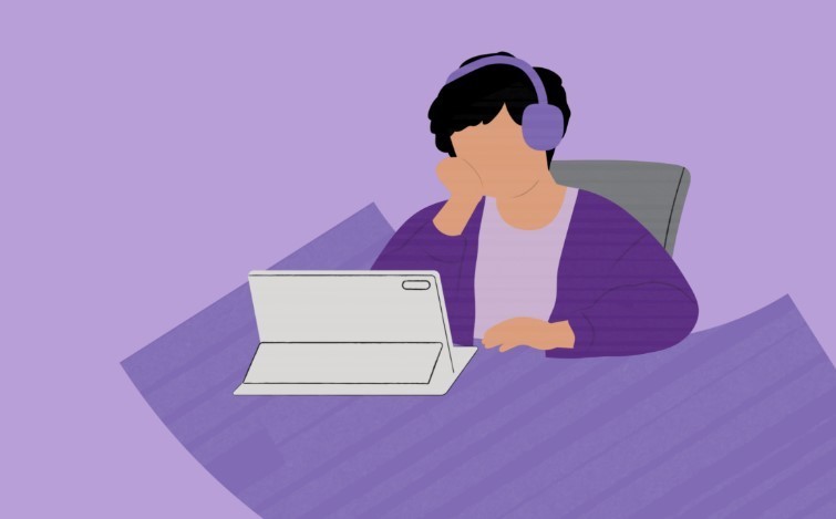 Student sitting at desk infront of computer wearing headphones