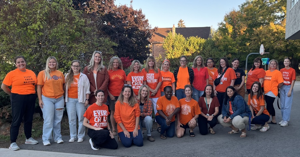 Many staff dressed in orange shirys with trees in the background.
