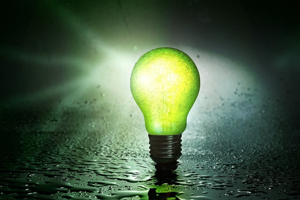 A green lightbulb is pictured in front of a green background.