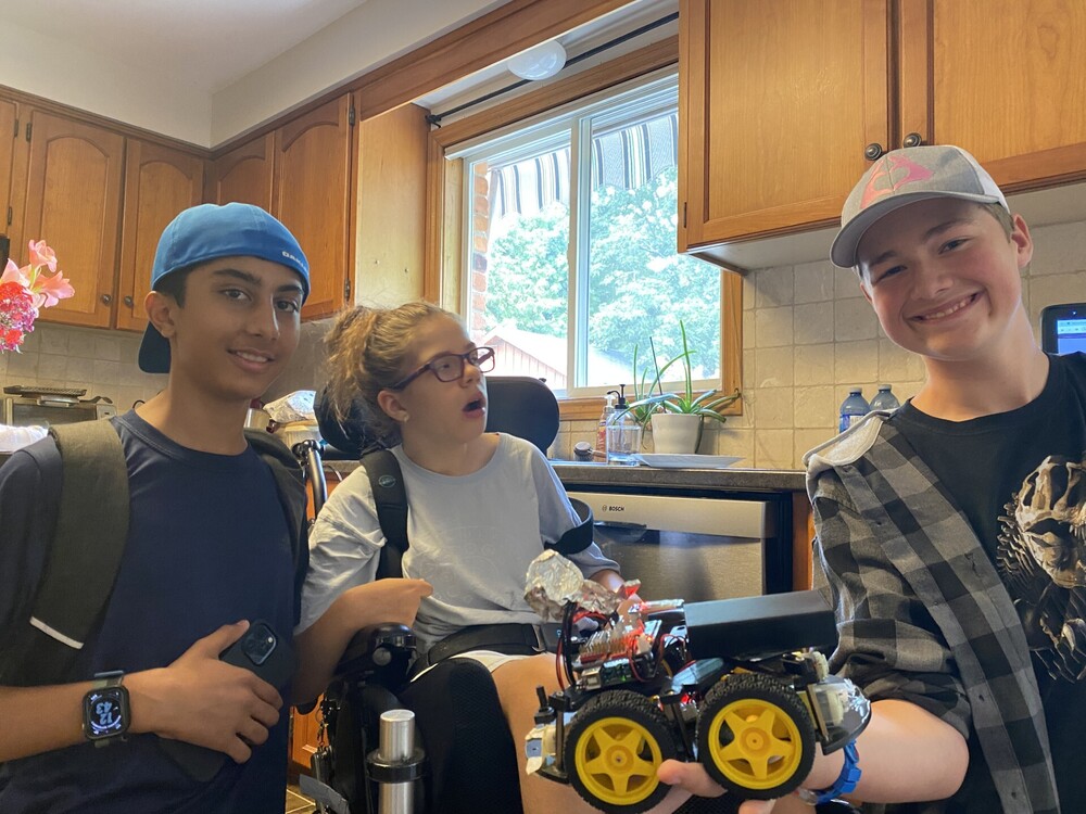 A photo of Rayyan, Scarlett, Owen, and the robotic car