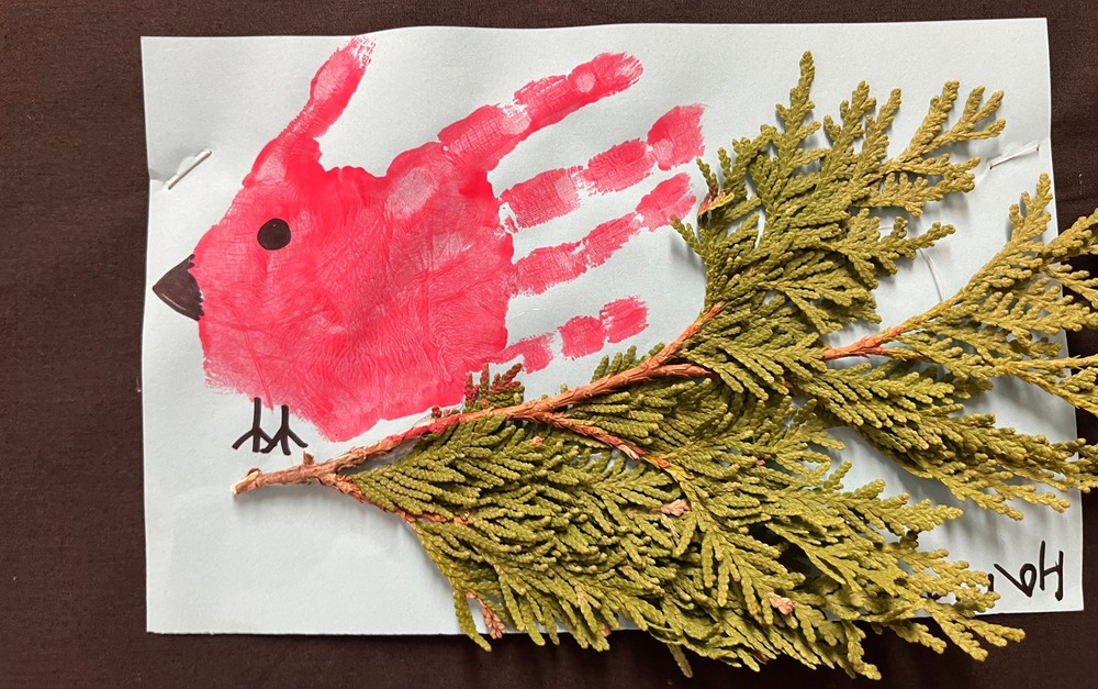 Red hand print that was made into a cardinal on a real cedar branch. 