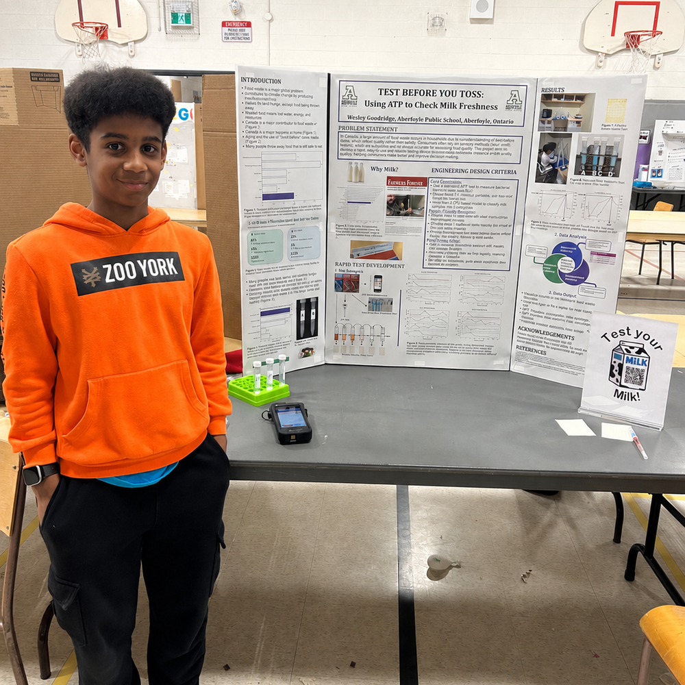 A student stands in front of a table with a display board.