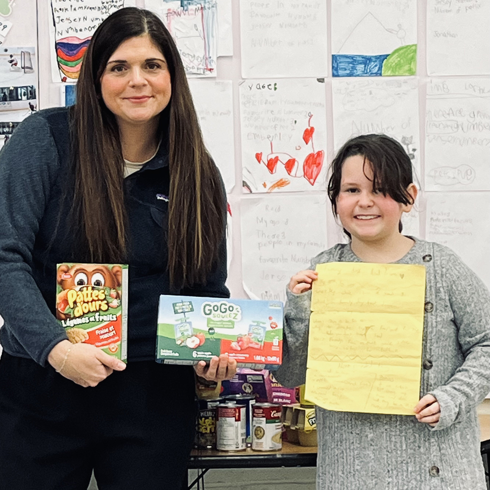 A teacher and a student pose for a photo in a classroom.