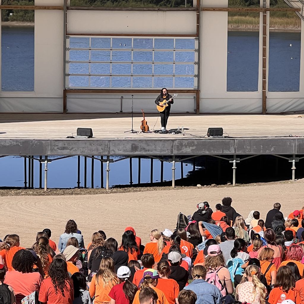 Students sit outside watching a concert at Island Lake Conversation Area. 