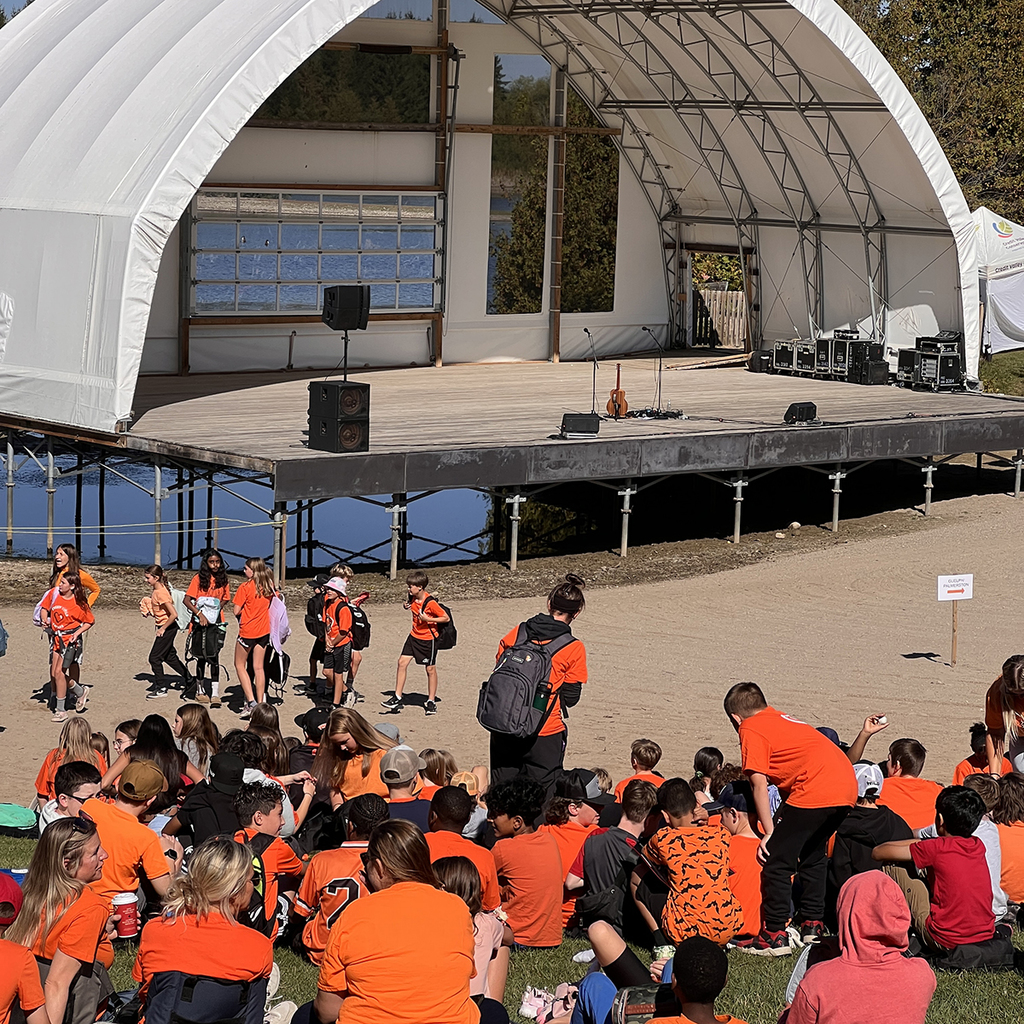Students sit outside watching a concert at Island Lake Conversation Area. 