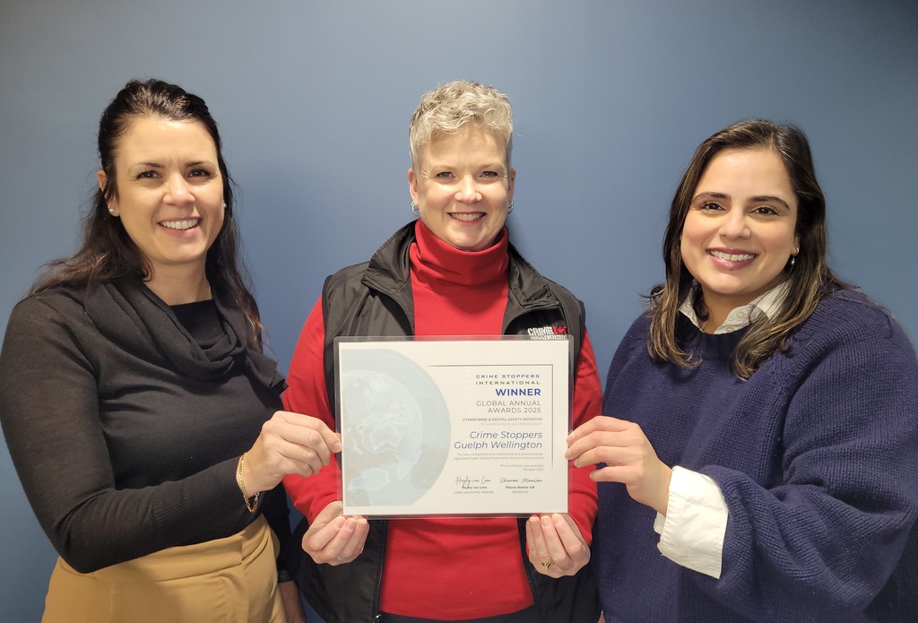 Three people pose for a photo, holding an award certificate. 