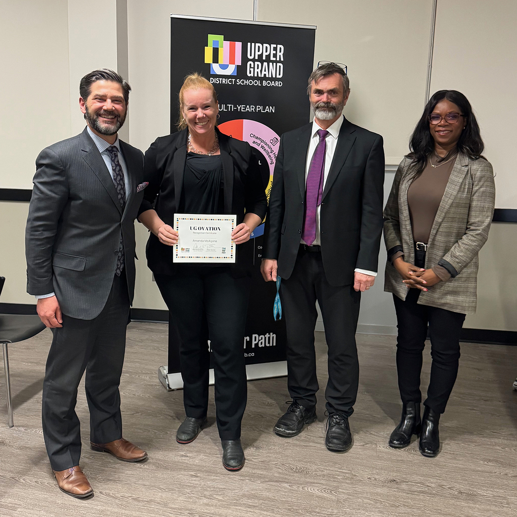 4 people pose for a photo in the Board Room.