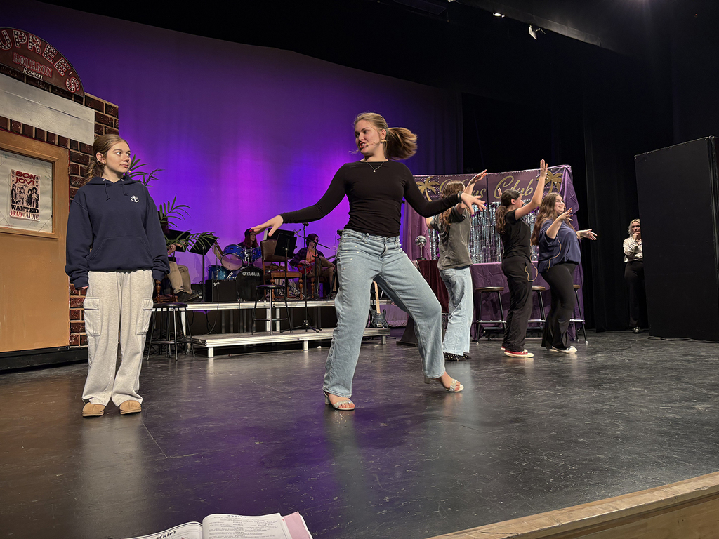 Students rehearse a school play on a stage. 
