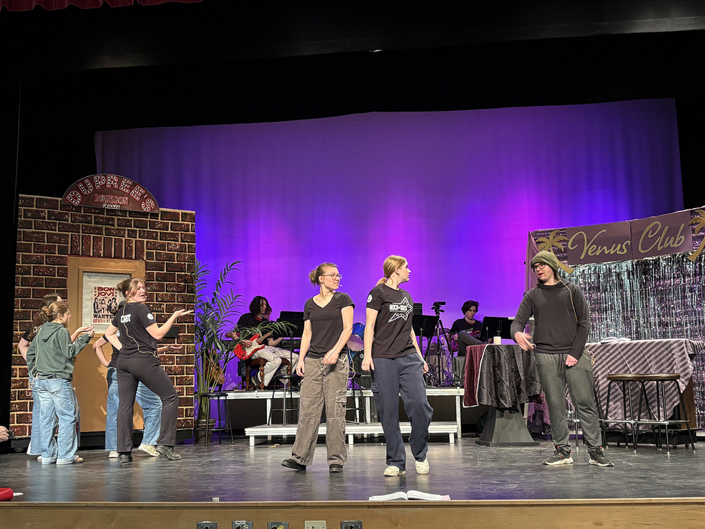 Students rehearse a school play on a stage. 