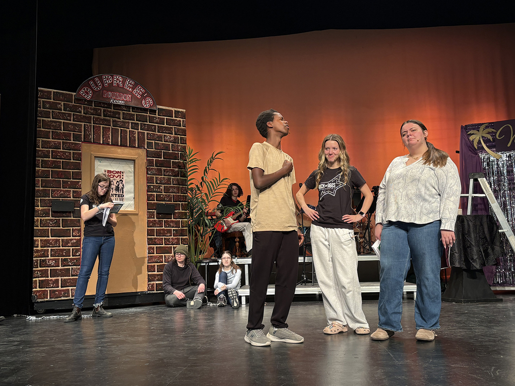 Students rehearse a school play on a stage. 