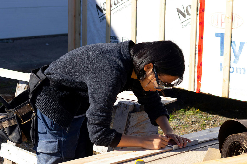 A female wearing safety glasses works on a construction project.