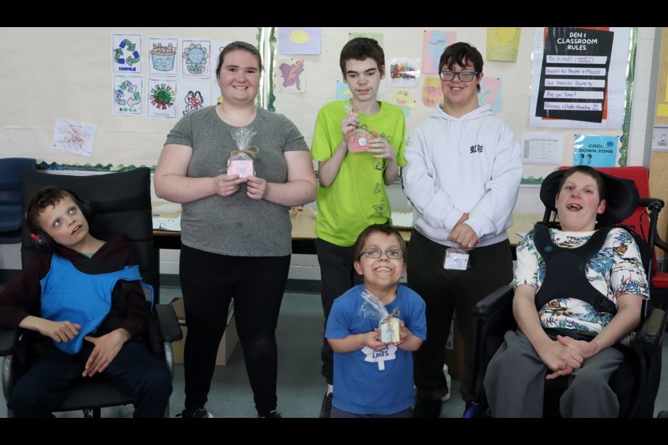 A group of smiling students in a classroom pose for a photo.