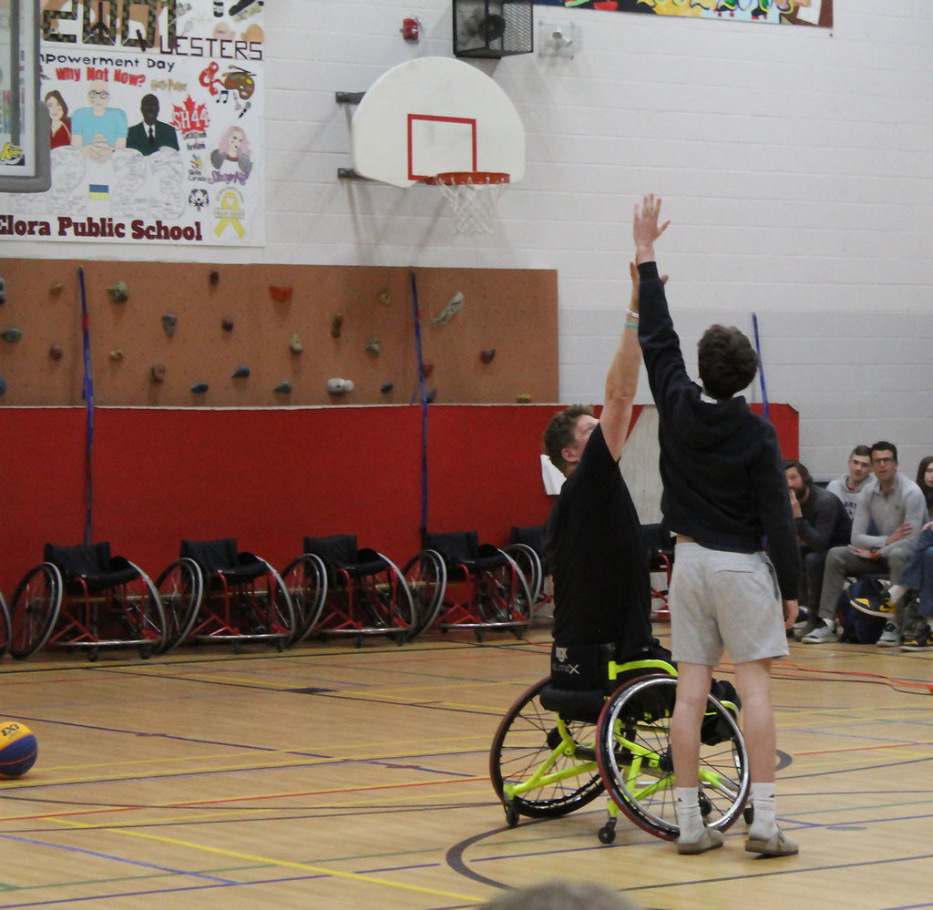 patrick anderson playing wheelchair basketball with a student