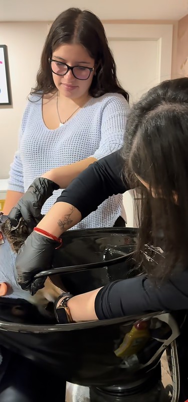 A student washes a clients hair at a hair salon.