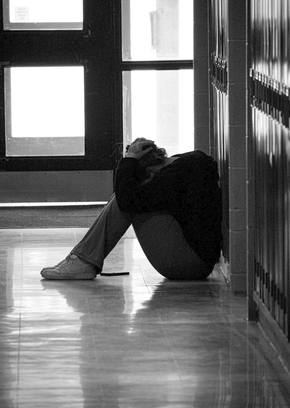 Black and white photo of a person sitting in a hallway