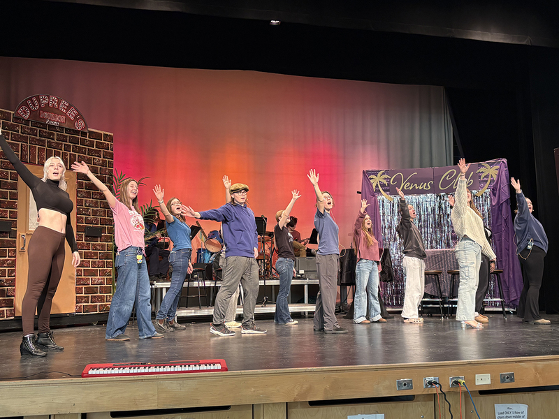 Students rehearse a play on a school stage.
