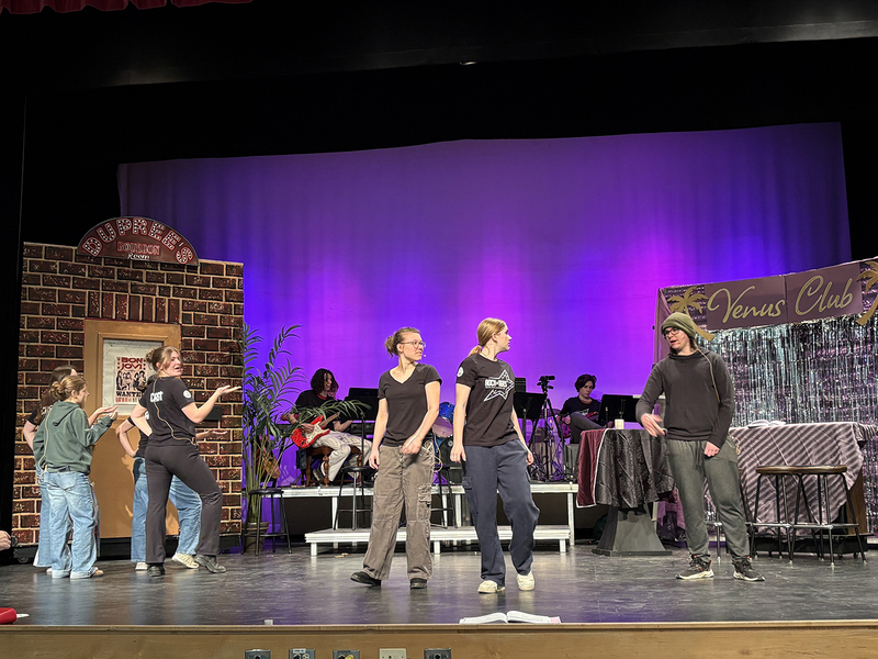 Students rehearse a play on a school stage.